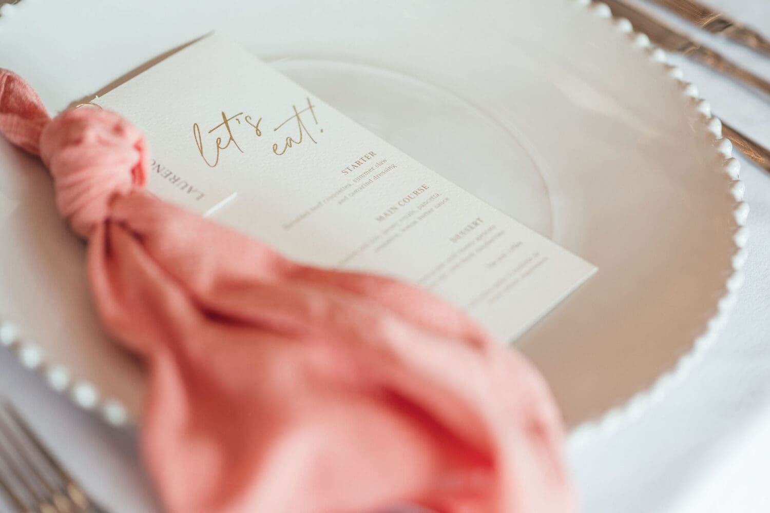 Banquet style table setting with coral linen and candlelight inside Wenmans Barn at Caswell House Oxfordshire, summer wedding photography by Hannah McClune Photography