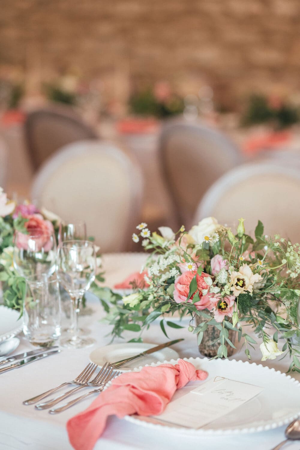 Banquet style table setting with coral linen and candlelight inside Wenmans Barn at Caswell House Oxfordshire, summer wedding photography by Hannah McClune Photography